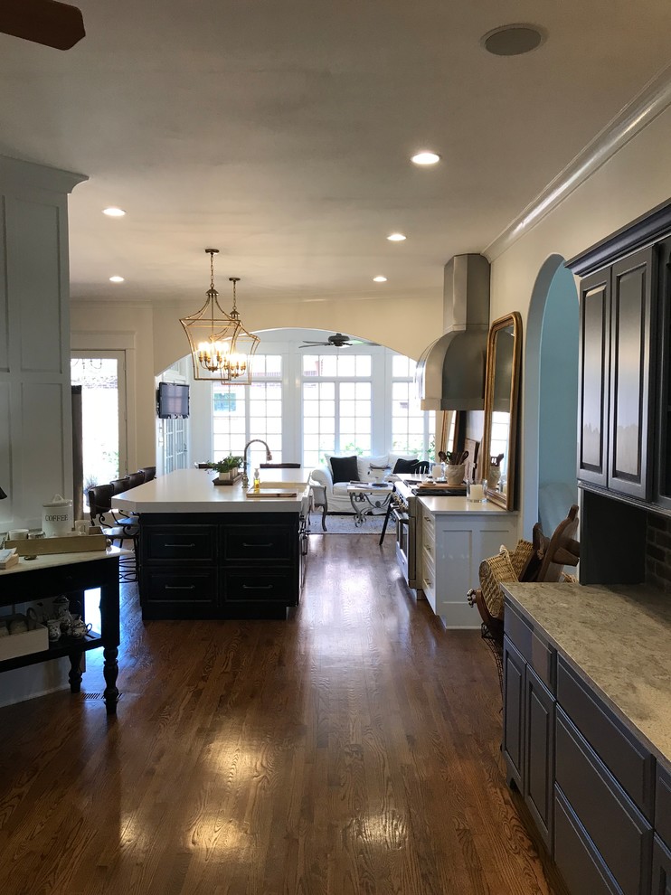 Expansive country single-wall open plan kitchen in Louisville with a farmhouse sink, beaded inset cabinets, white cabinets, quartz benchtops, brown splashback, brick splashback, stainless steel appliances, medium hardwood floors, with island, brown floor and white benchtop.