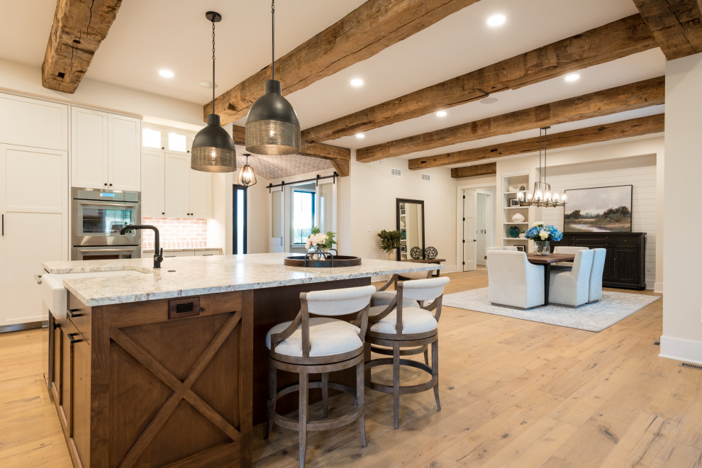Photo of an expansive country single-wall kitchen/diner in Other with brick splashback, medium hardwood flooring, an island, brown floors and exposed beams.