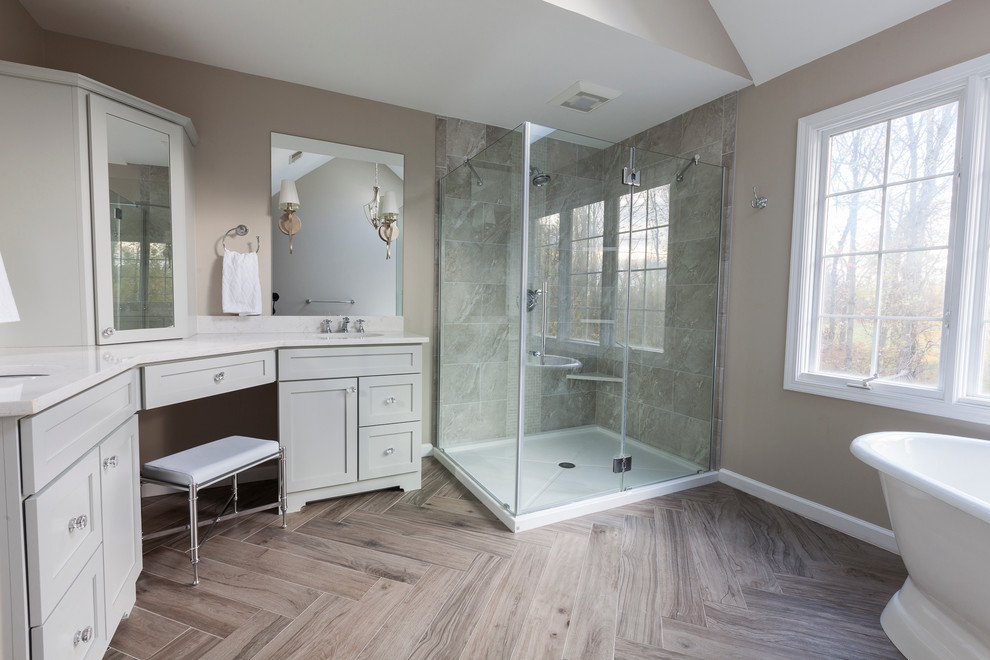 Example of a mid-sized transitional master gray tile and porcelain tile porcelain tile and gray floor freestanding bathtub design in New York with flat-panel cabinets, gray cabinets, a two-piece toilet, gray walls, an undermount sink, quartz countertops and a hinged shower door