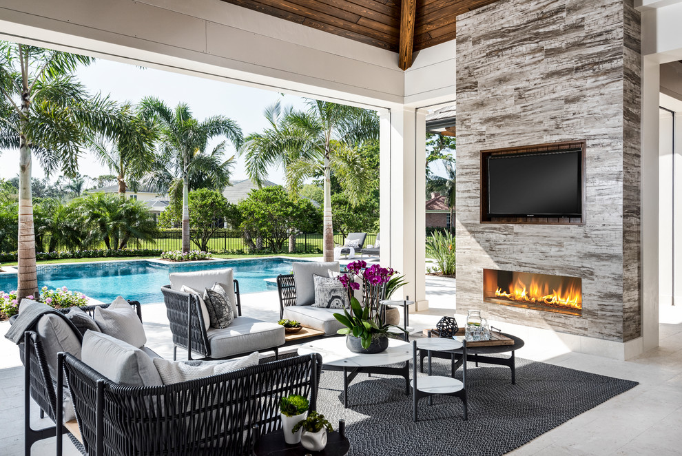 This is an example of a beach style backyard patio in Other with tile, a roof extension and with fireplace.