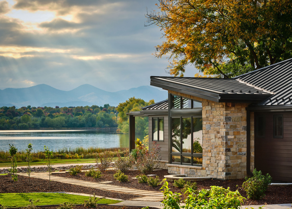 Large trendy brown one-story stone house exterior photo in Denver with a metal roof and a brown roof