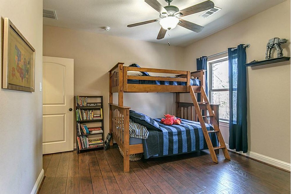 Mid-sized mediterranean guest bedroom in Houston with beige walls and dark hardwood floors.
