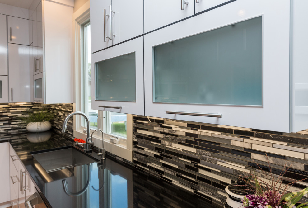 Open concept kitchen - large contemporary u-shaped light wood floor open concept kitchen idea with an undermount sink, flat-panel cabinets, white cabinets, granite countertops, multicolored backsplash, mosaic tile backsplash, stainless steel appliances and an island