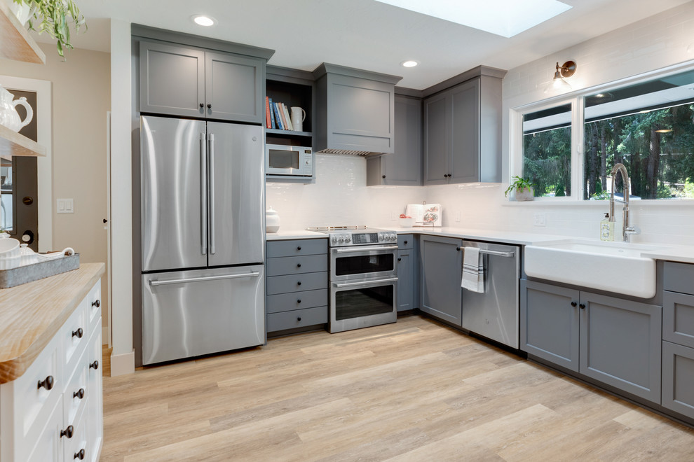 Design ideas for a country eat-in kitchen in Portland with a farmhouse sink, grey cabinets, quartzite benchtops, white splashback, subway tile splashback, stainless steel appliances and white benchtop.