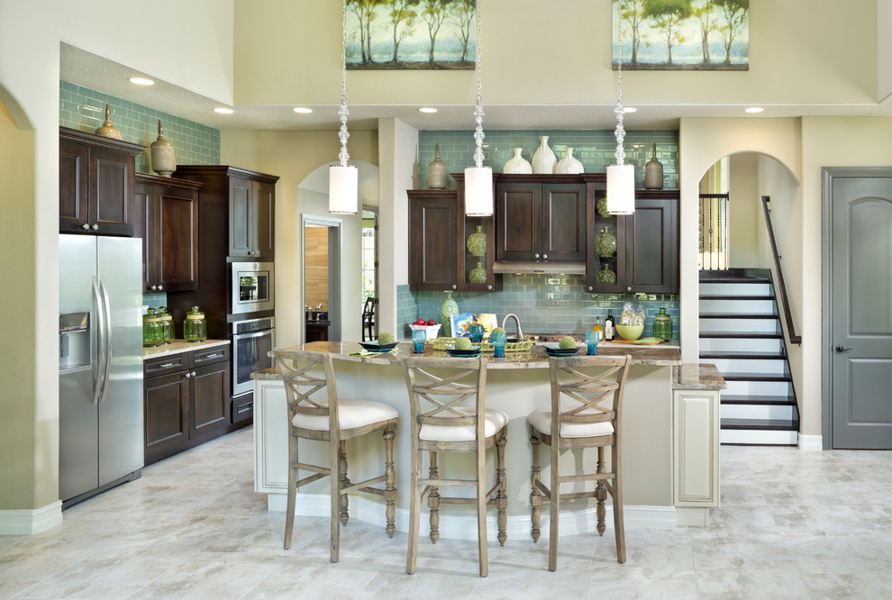Inspiration for a traditional l-shaped kitchen in Orlando with recessed-panel cabinets, dark wood cabinets, blue splashback, subway tile splashback, stainless steel appliances and with island.