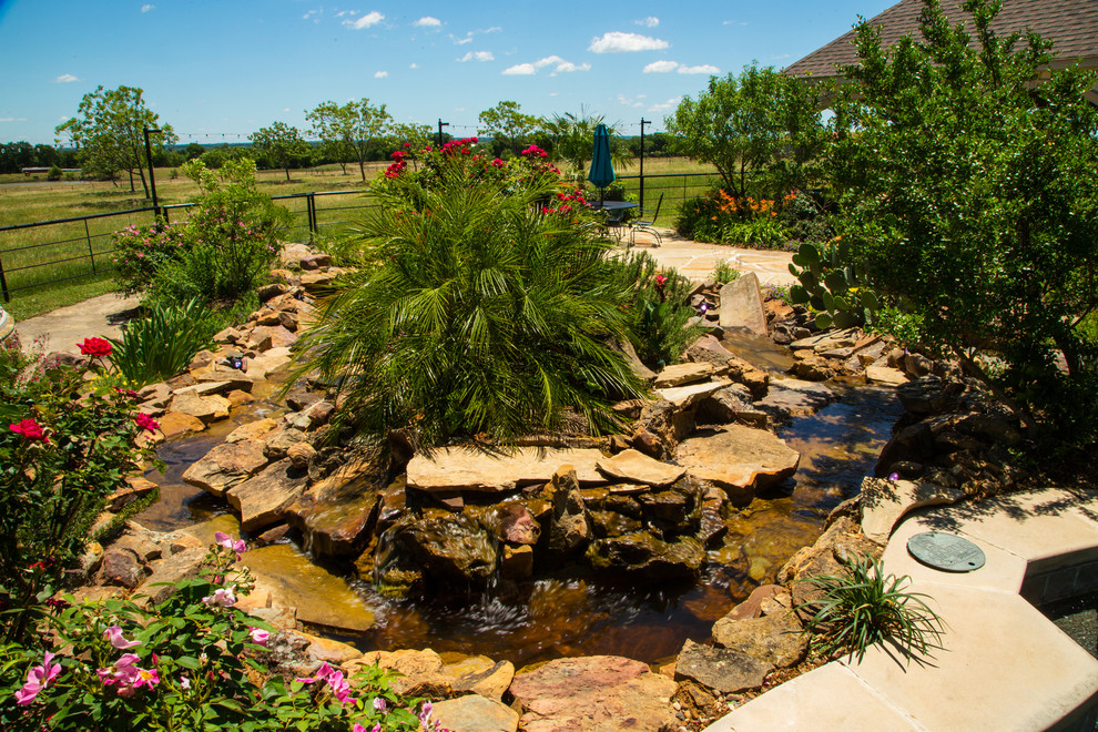 Inspiration for a large country backyard full sun xeriscape in Dallas with with pond and natural stone pavers.