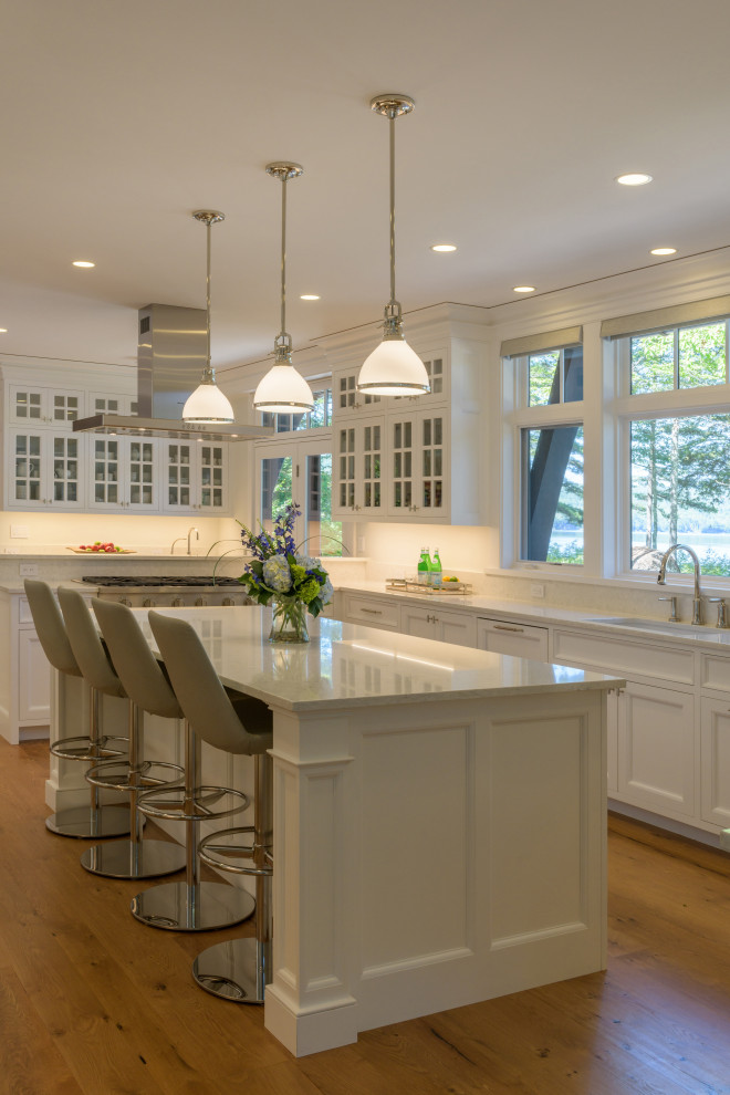 Transitional kitchen in Boston with an undermount sink, recessed-panel cabinets, white cabinets, stainless steel appliances, medium hardwood floors, with island, brown floor and white benchtop.