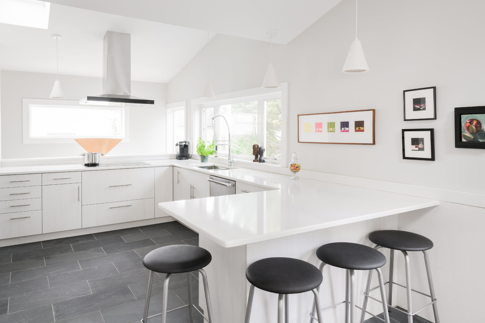 Mid-sized modern u-shaped eat-in kitchen in Boston with a double-bowl sink, flat-panel cabinets, white cabinets, marble benchtops, white splashback, marble splashback, stainless steel appliances, slate floors, no island and black floor.