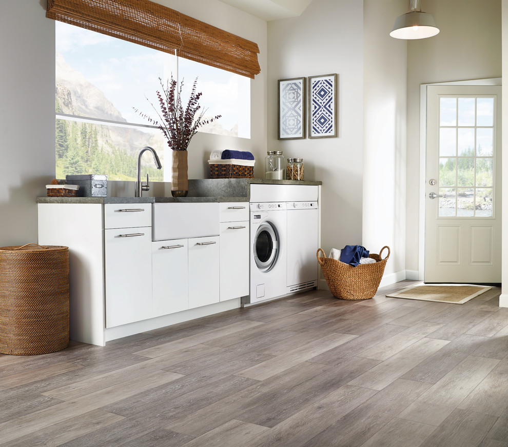 Design ideas for a large transitional single-wall laundry room in Other with a farmhouse sink, flat-panel cabinets, white cabinets, granite benchtops, white walls, a side-by-side washer and dryer, vinyl floors, beige floor and grey benchtop.