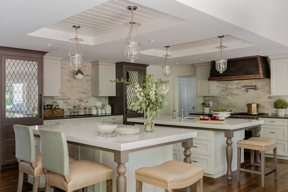 Inspiration for a large traditional single-wall kitchen in Boston with an undermount sink, recessed-panel cabinets, beige cabinets, beige splashback, medium hardwood floors, multiple islands, stainless steel appliances and brown floor.