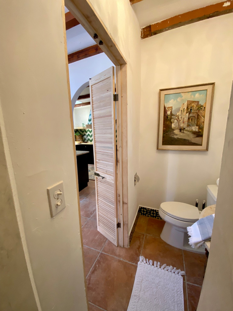 Идея дизайна: маленькая ванная комната в белых тонах с отделкой деревом в средиземноморском стиле с искусственно-состаренными фасадами, открытым душем, раздельным унитазом, белой плиткой, цементной плиткой, белыми стенами, полом из терракотовой плитки, душевой кабиной, настольной раковиной, мраморной столешницей, оранжевым полом, открытым душем, бежевой столешницей, тумбой под одну раковину, напольной тумбой и балками на потолке для на участке и в саду