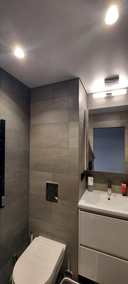 Источник вдохновения для домашнего уюта: маленькая серо-белая ванная комната в современном стиле с плоскими фасадами, белыми фасадами, душем в нише, инсталляцией, серой плиткой, керамогранитной плиткой, серыми стенами, полом из керамогранита, душевой кабиной, накладной раковиной, серым полом, шторкой для ванной, гигиеническим душем, тумбой под одну раковину и подвесной тумбой для на участке и в саду
