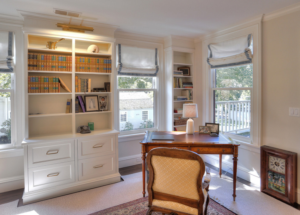 Mittelgroßes Klassisches Lesezimmer ohne Kamin mit beiger Wandfarbe, dunklem Holzboden, freistehendem Schreibtisch und braunem Boden in Bridgeport