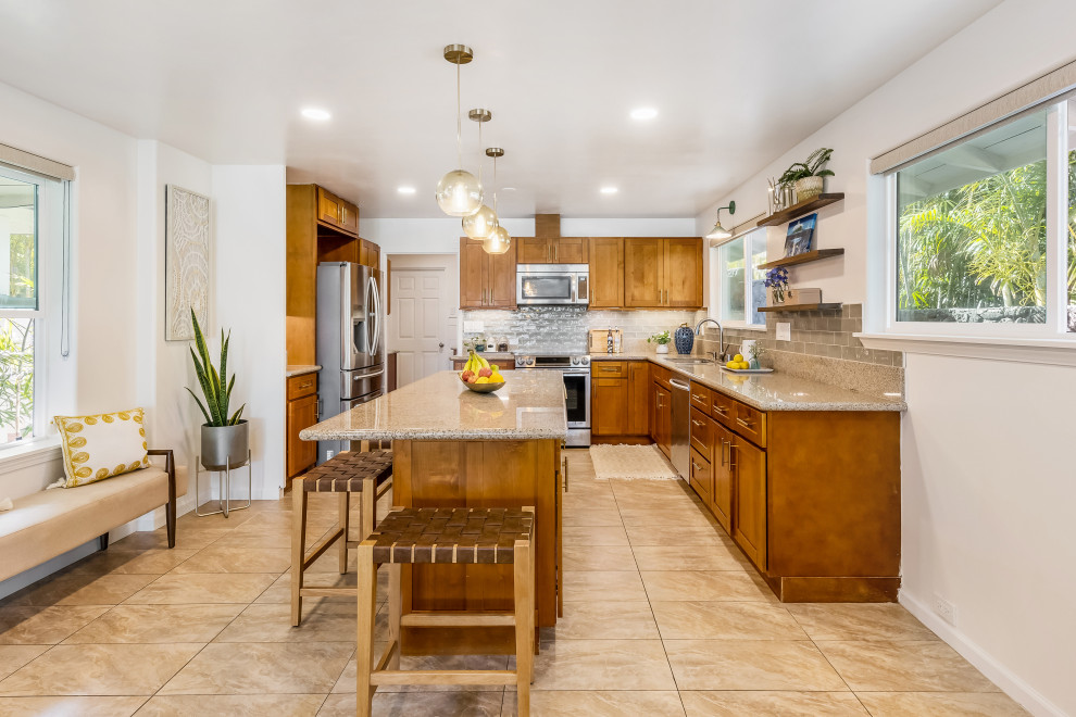 Photo of a large transitional u-shaped eat-in kitchen in Hawaii with an undermount sink, shaker cabinets, orange cabinets, granite benchtops, green splashback, subway tile splashback, stainless steel appliances, travertine floors, with island, beige floor and multi-coloured benchtop.