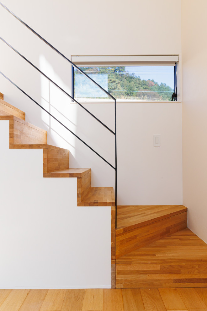 Идея дизайна: деревянная лестница в скандинавском стиле с деревянными ступенями, металлическими перилами, обоями на стенах и кладовкой или шкафом под ней