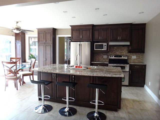 Eat-in kitchen - large transitional galley porcelain tile eat-in kitchen idea in Toronto with an undermount sink, raised-panel cabinets, dark wood cabinets, granite countertops, multicolored backsplash, mosaic tile backsplash and an island