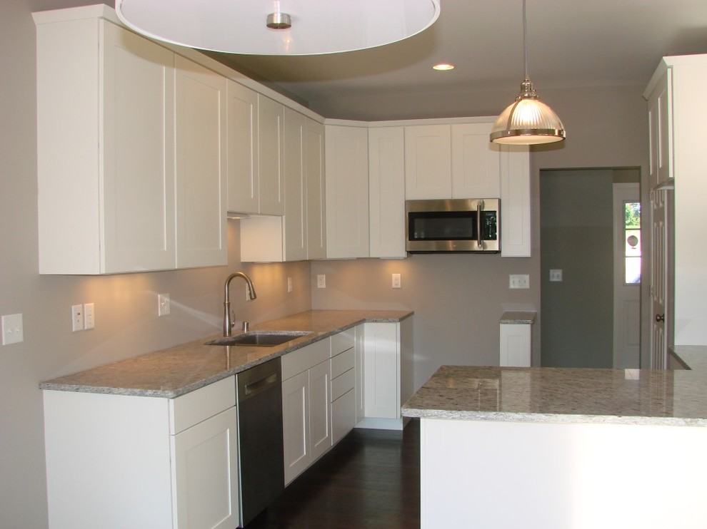Example of a transitional dark wood floor eat-in kitchen design with a double-bowl sink, shaker cabinets, white cabinets, granite countertops and stainless steel appliances