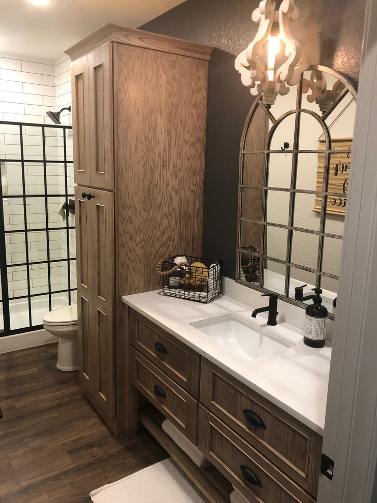 This is an example of a mid-sized industrial master bathroom in Other with shaker cabinets, brown cabinets, a claw-foot tub, an alcove shower, a one-piece toilet, white tile, subway tile, brown walls, vinyl floors, a drop-in sink, engineered quartz benchtops, brown floor, a hinged shower door and multi-coloured benchtops.