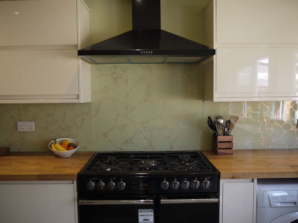 This is an example of a contemporary kitchen in London with green splashback and glass sheet splashback.