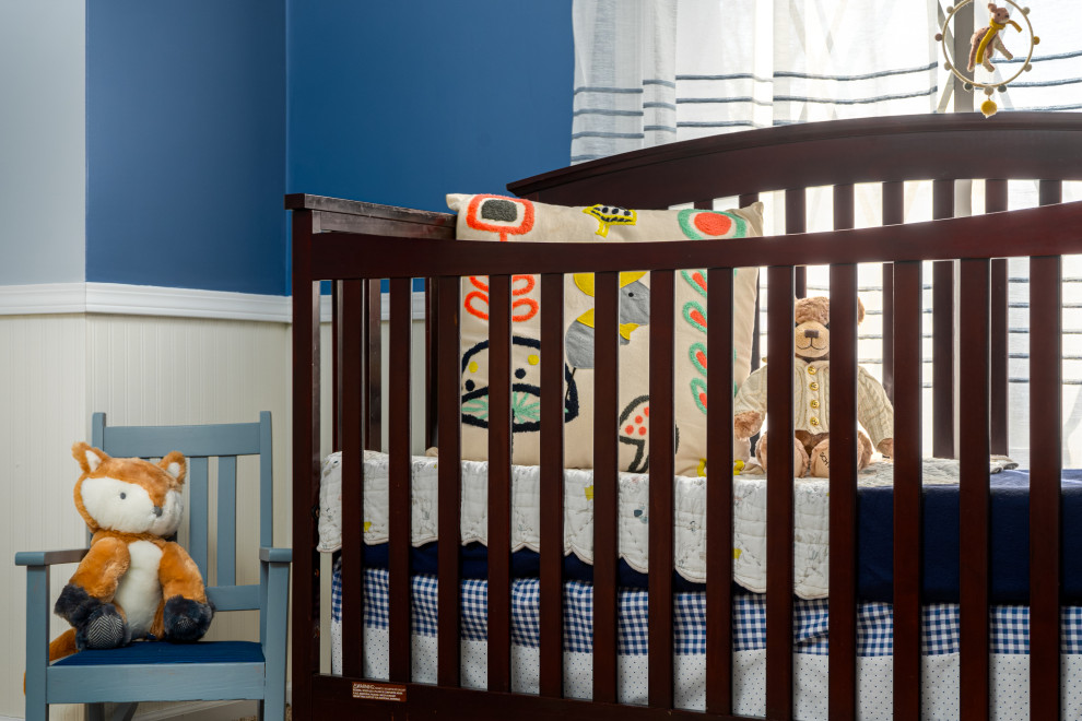 Photo of a mid-sized transitional nursery for boys in Grand Rapids with blue walls, carpet, beige floor and decorative wall panelling.