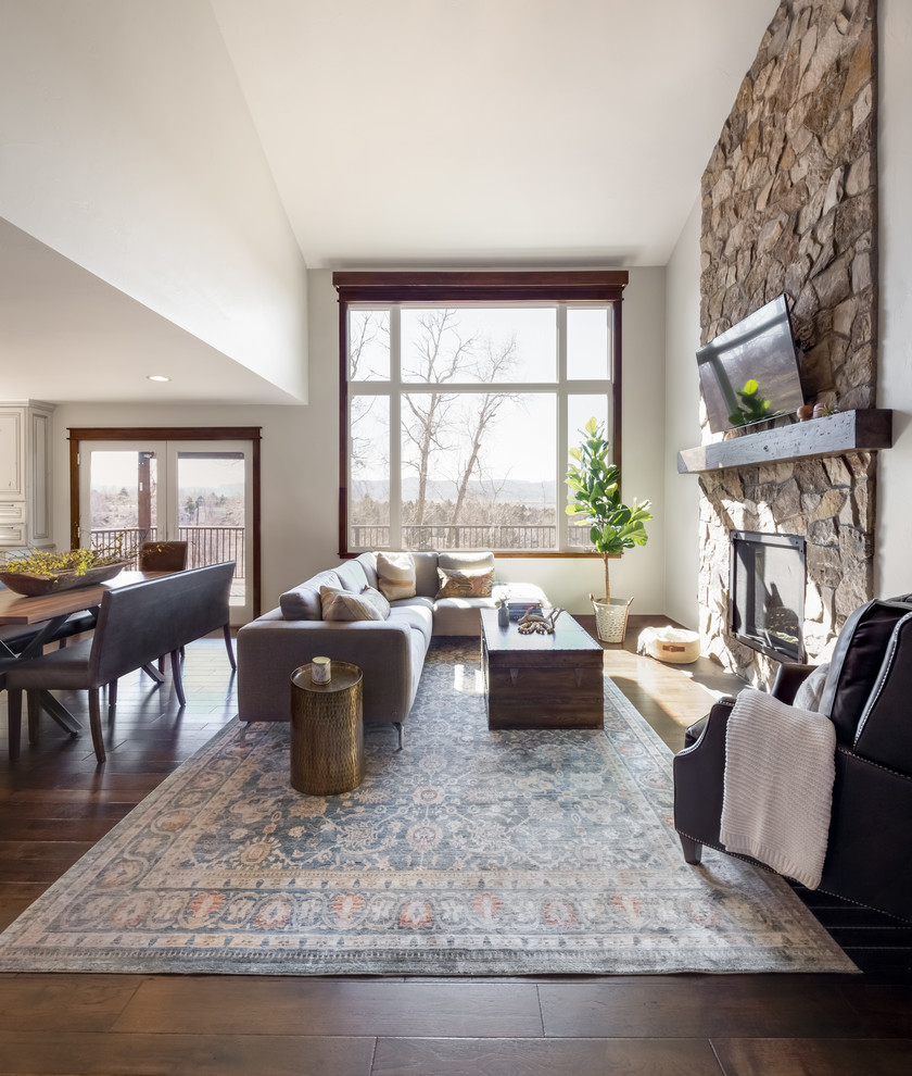 Mid-sized transitional open concept dark wood floor, brown floor and vaulted ceiling living room photo in Denver with a standard fireplace, a stone fireplace and a wall-mounted tv