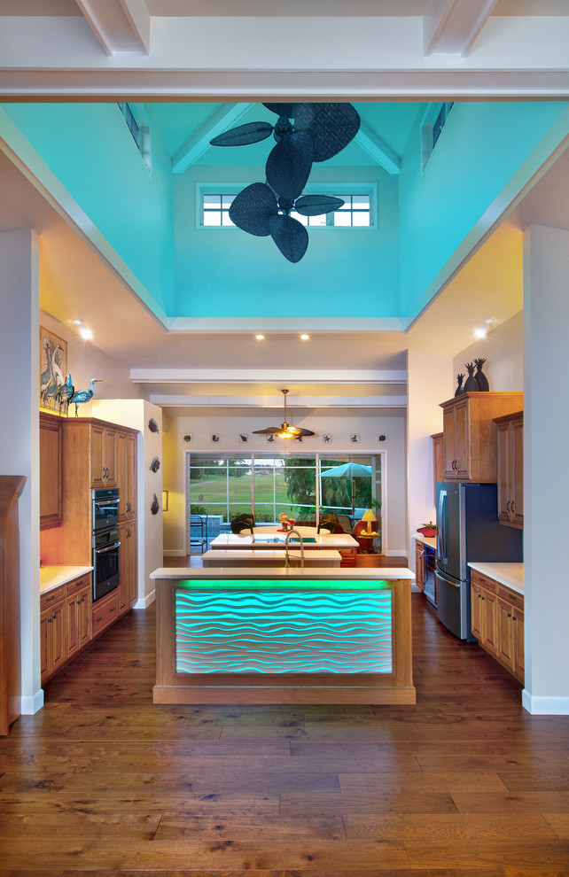 Inspiration for a large tropical galley open plan kitchen in Miami with an undermount sink, raised-panel cabinets, medium wood cabinets, quartz benchtops, white splashback, stone tile splashback, stainless steel appliances, medium hardwood floors, multiple islands, brown floor and white benchtop.