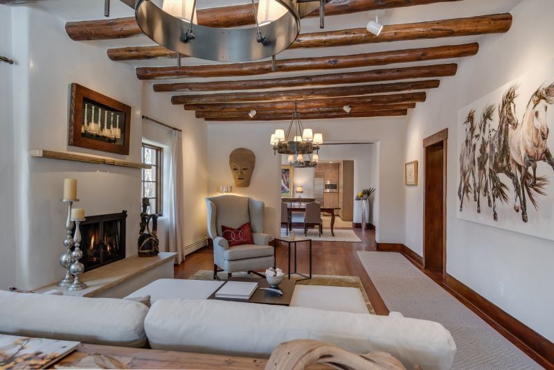 Photo of a large formal open concept living room in Albuquerque with white walls, medium hardwood floors, a standard fireplace, a plaster fireplace surround and no tv.