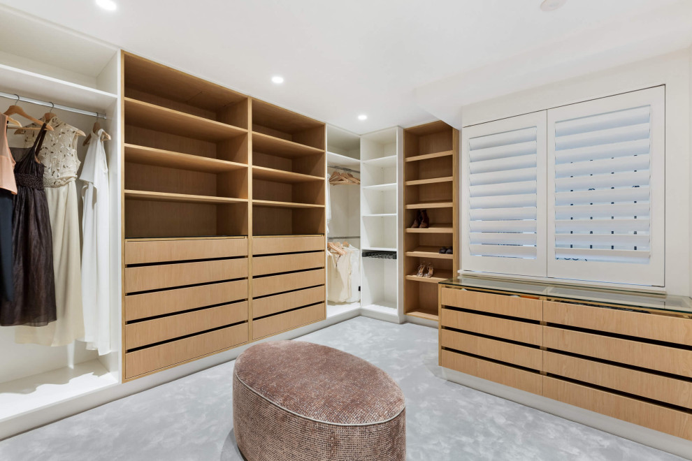 Photo of a large contemporary women's walk-in wardrobe in Sydney with open cabinets, light wood cabinets, carpet and grey floor.