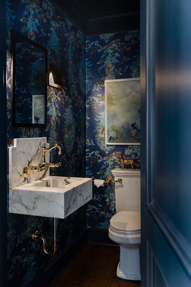 Cette photo montre un WC et toilettes chic avec WC séparés, un mur bleu, parquet foncé, un lavabo suspendu, un sol marron et du papier peint.