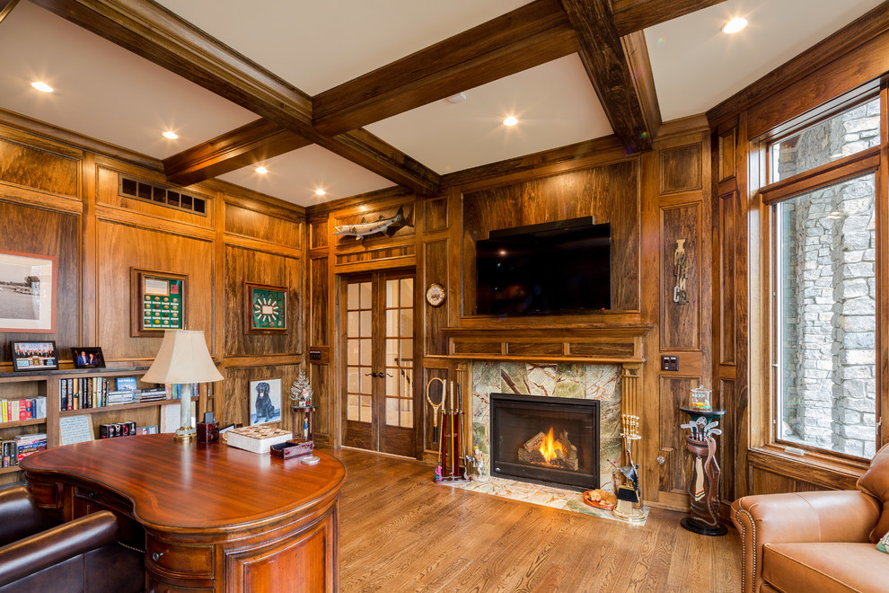 This is an example of a traditional study room in Cincinnati with medium hardwood floors, a standard fireplace, a stone fireplace surround and a freestanding desk.