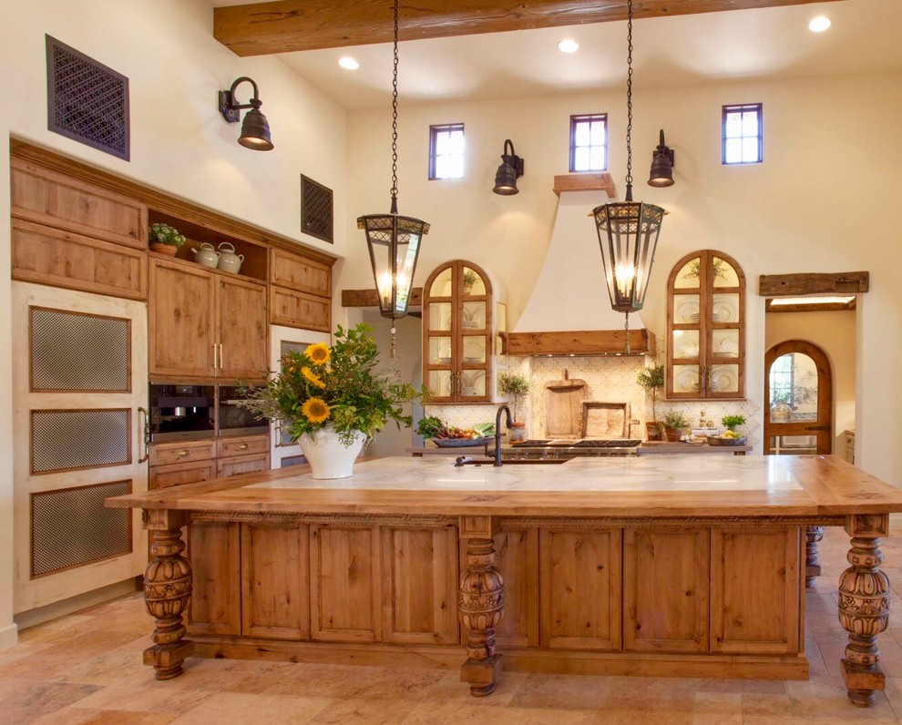 This is an example of a large mediterranean l-shaped eat-in kitchen in San Diego with a farmhouse sink, beige splashback, mosaic tile splashback, stainless steel appliances, ceramic floors, beige floor, recessed-panel cabinets, medium wood cabinets, wood benchtops and with island.