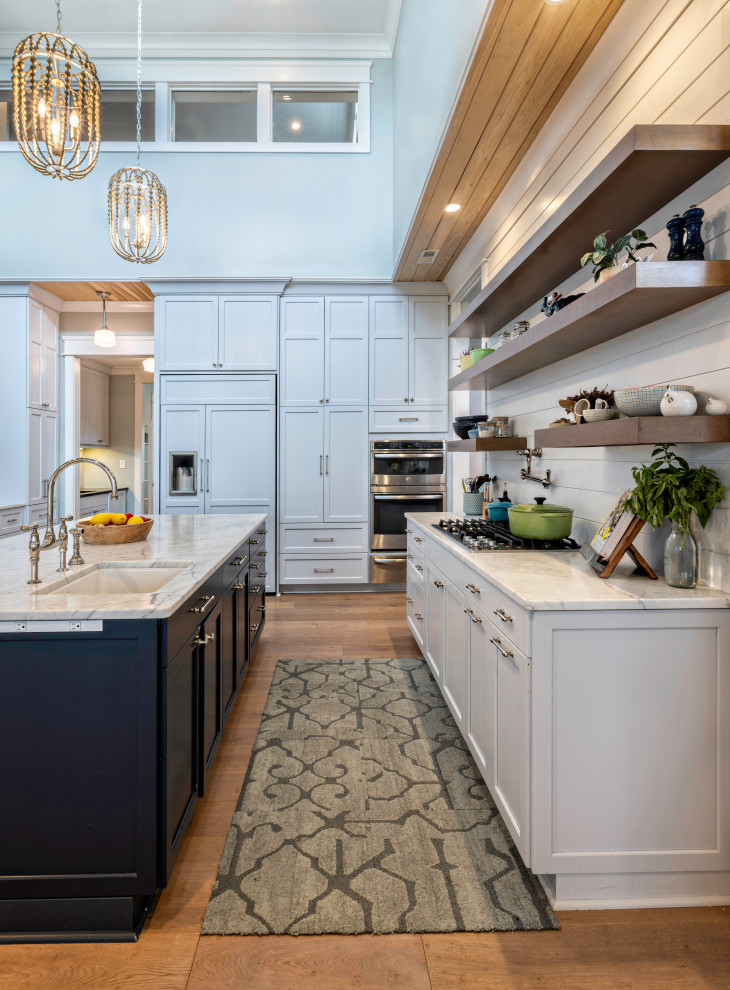 Kitchen - coastal u-shaped medium tone wood floor and brown floor kitchen idea with an undermount sink, shaker cabinets, white cabinets, white backsplash, shiplap backsplash, paneled appliances, an island and white countertops