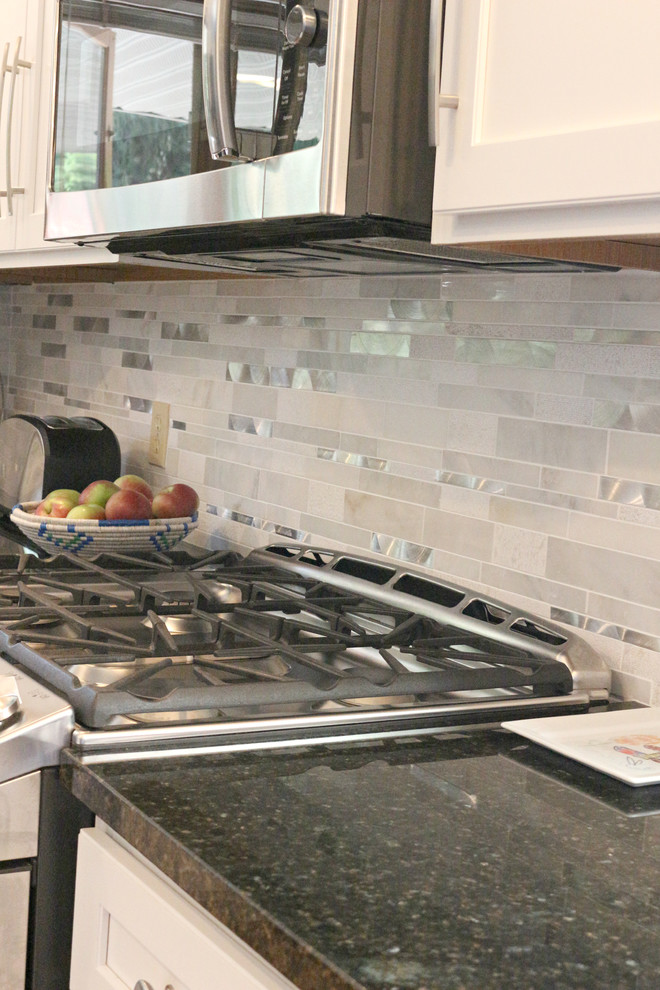 Large transitional l-shaped medium tone wood floor eat-in kitchen photo with an undermount sink, shaker cabinets, white cabinets, granite countertops, gray backsplash, matchstick tile backsplash, stainless steel appliances and an island
