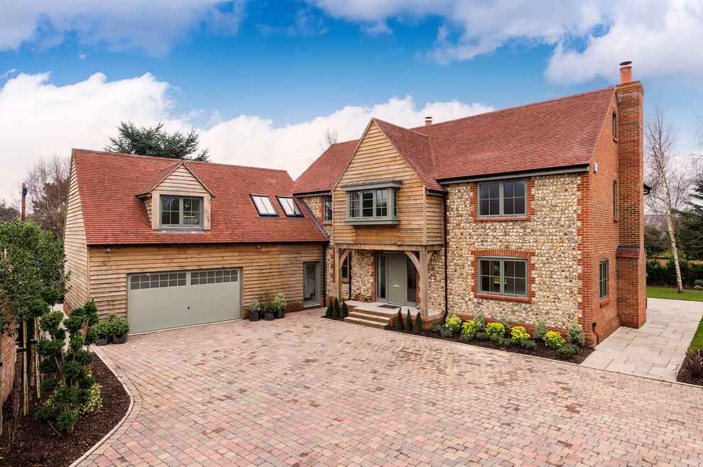 This is an example of an expansive contemporary three-storey multi-coloured house exterior in Hampshire with wood siding, a gable roof and a tile roof.