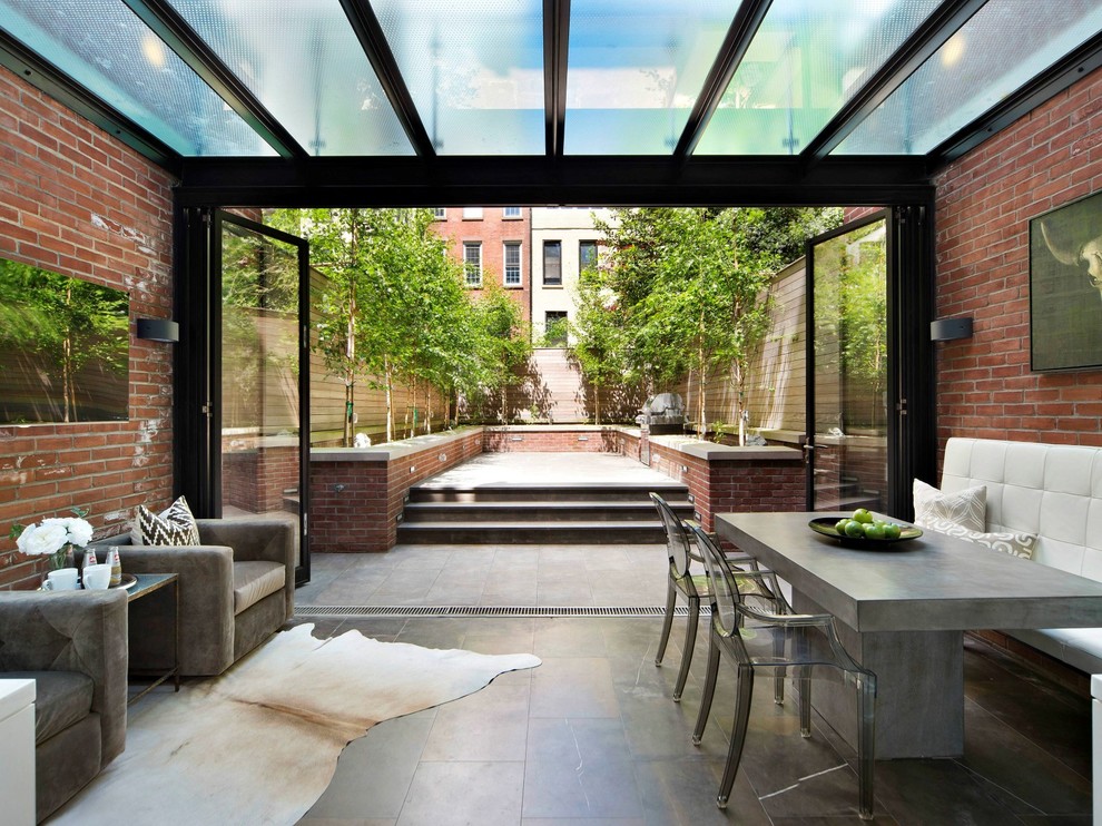 Transitional sunroom in New York with a glass ceiling and grey floor.
