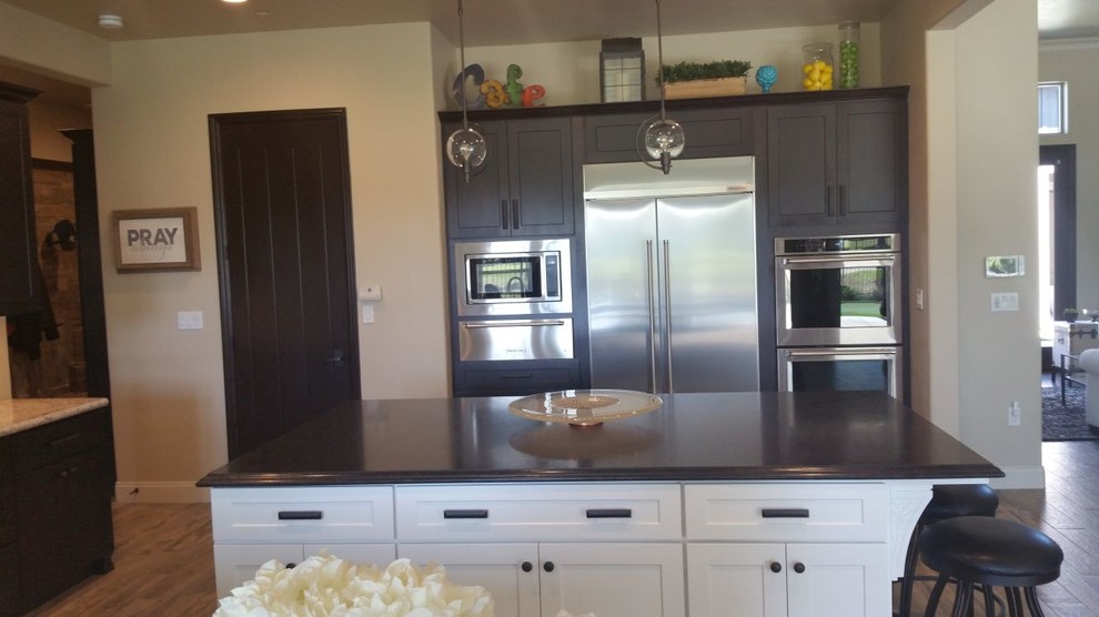 Inspiration for a large transitional u-shaped brown floor open concept kitchen remodel with an undermount sink, recessed-panel cabinets, dark wood cabinets, granite countertops, beige backsplash, porcelain backsplash, stainless steel appliances and an island