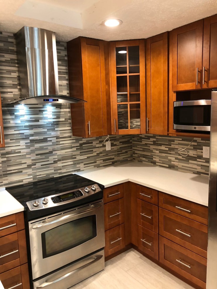 Enclosed kitchen - mid-sized transitional u-shaped porcelain tile and gray floor enclosed kitchen idea in Houston with an undermount sink, shaker cabinets, medium tone wood cabinets, quartz countertops, multicolored backsplash, glass tile backsplash, stainless steel appliances, no island and white countertops