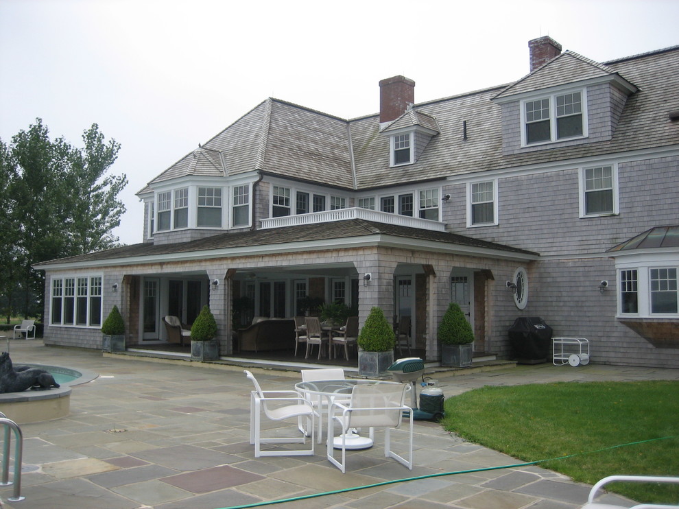 Large beach style three-storey grey house exterior in New York with wood siding, a hip roof and a shingle roof.