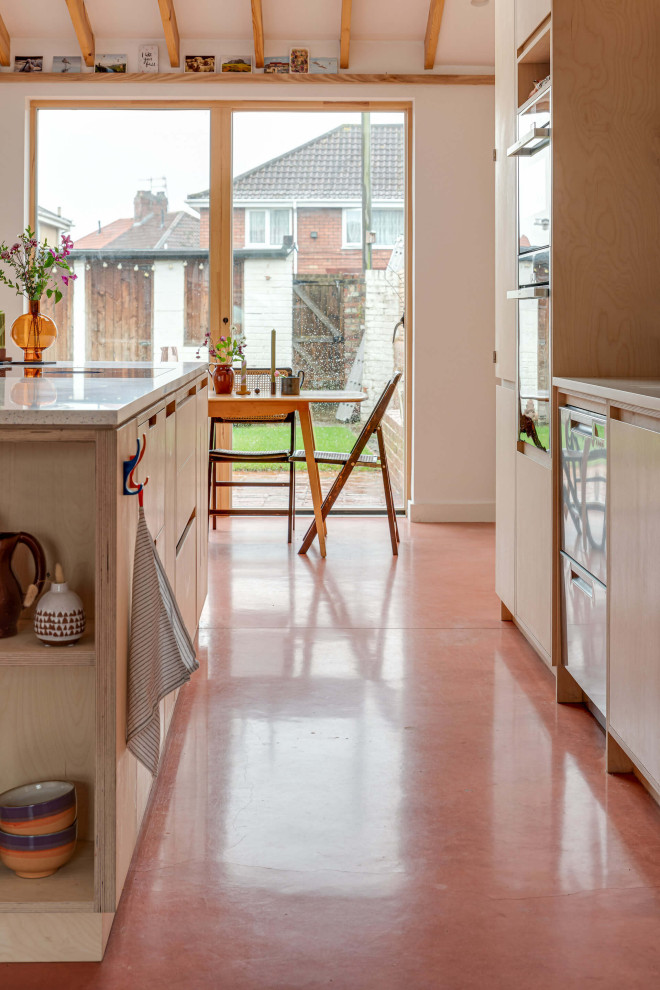 Offene, Zweizeilige, Große Moderne Küche mit flächenbündigen Schrankfronten, hellen Holzschränken, Betonboden, Kücheninsel und rosa Boden in Gloucestershire