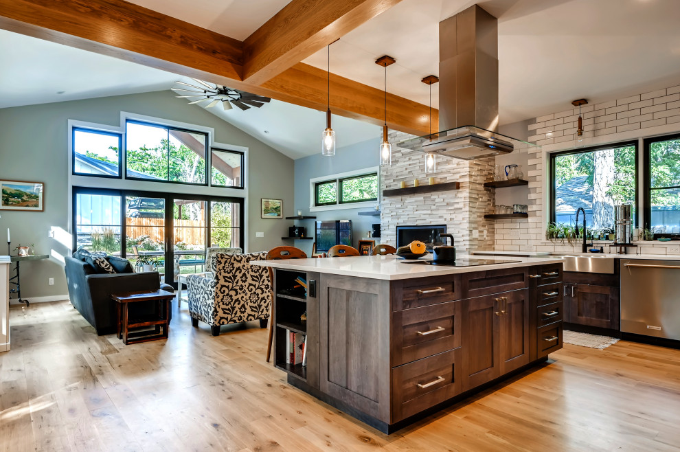 Photo of a mid-sized contemporary l-shaped eat-in kitchen in Denver with a farmhouse sink, shaker cabinets, dark wood cabinets, quartzite benchtops, beige splashback, subway tile splashback, stainless steel appliances, light hardwood floors, with island, brown floor, beige benchtop and exposed beam.