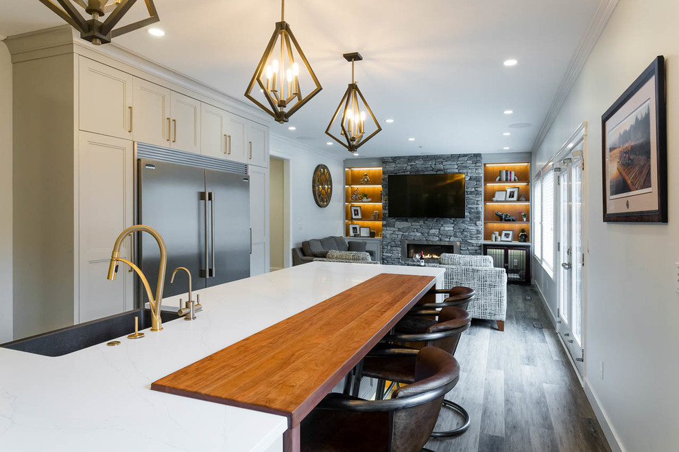 Large transitional l-shaped eat-in kitchen in Vancouver with a farmhouse sink, shaker cabinets, grey cabinets, quartz benchtops, grey splashback, marble splashback, dark hardwood floors, with island, brown floor and white benchtop.