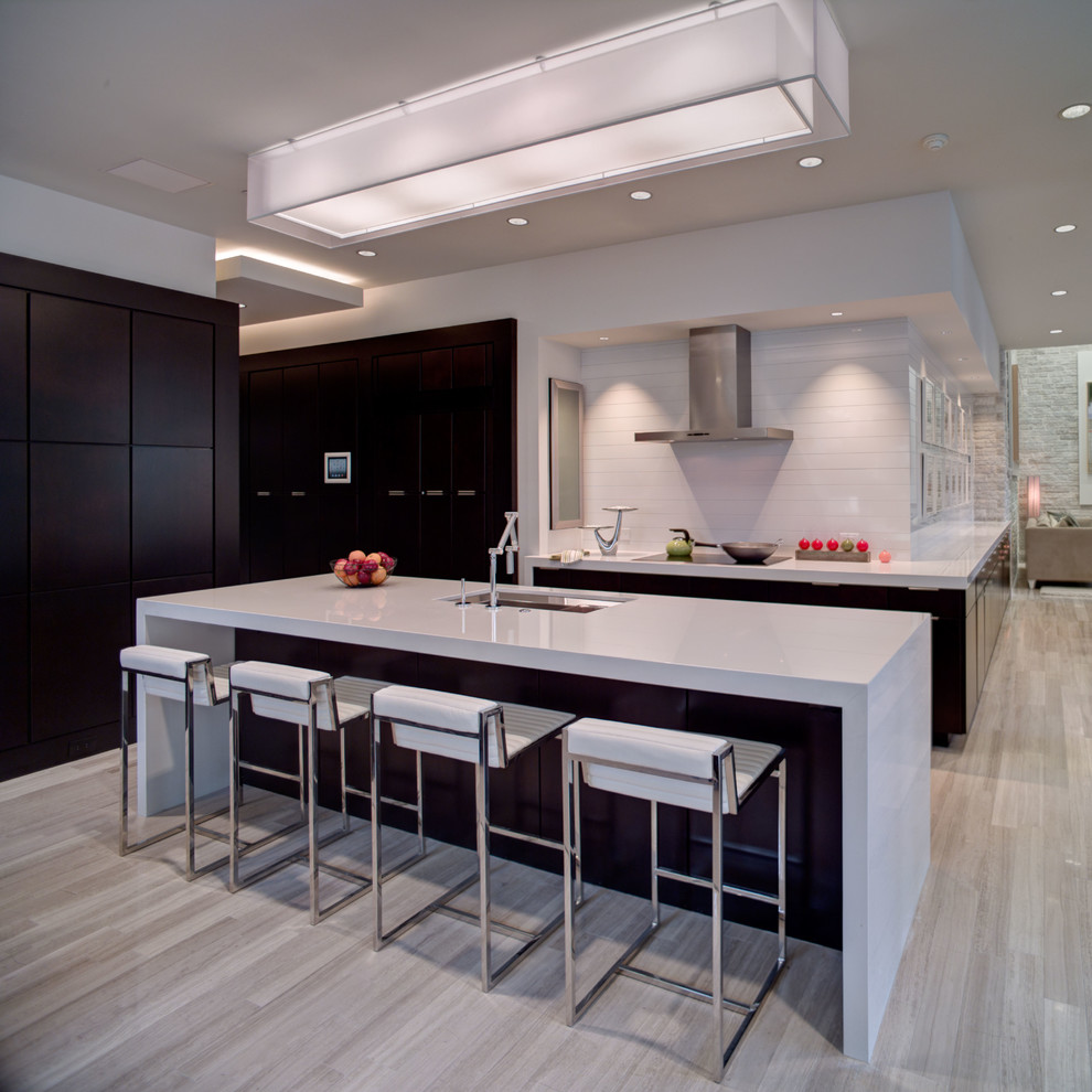 This is an example of a contemporary single-wall kitchen in Orlando with dark wood cabinets, white splashback, with island, flat-panel cabinets, quartzite benchtops, limestone floors and panelled appliances.