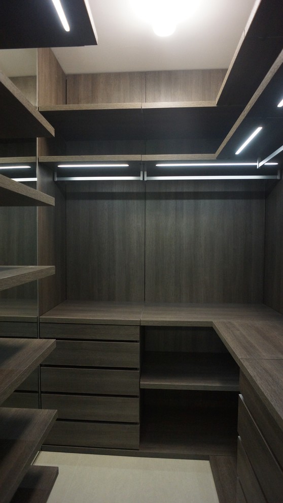 Small modern men's walk-in wardrobe in Miami with dark wood cabinets and porcelain floors.