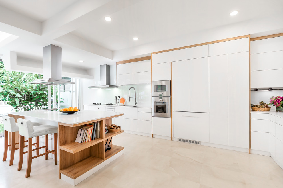 Photo of a large scandinavian l-shaped eat-in kitchen in Singapore with an undermount sink, flat-panel cabinets, white cabinets, white splashback, glass sheet splashback, stainless steel appliances and with island.