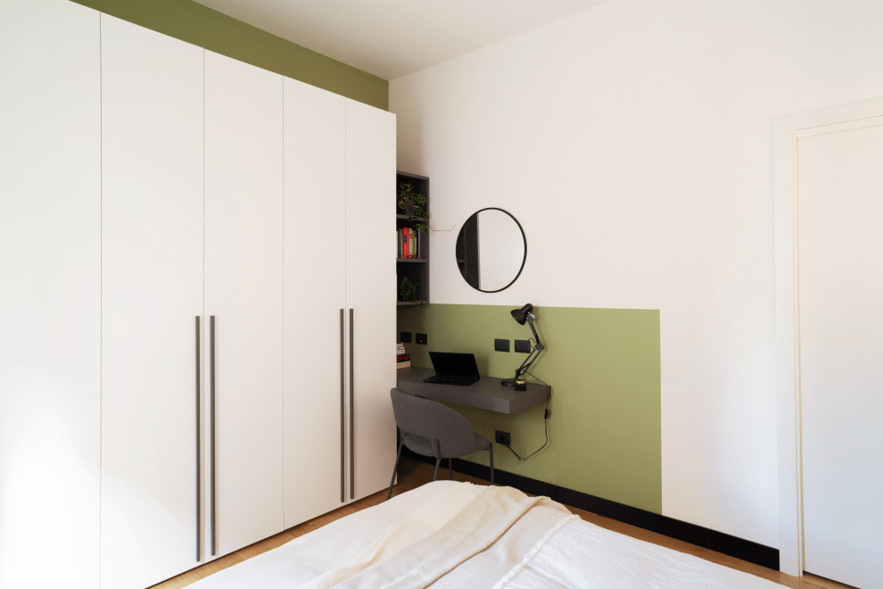 Esempio di una camera matrimoniale moderna di medie dimensioni con pareti verdi, parquet chiaro, pavimento marrone e angolo studio