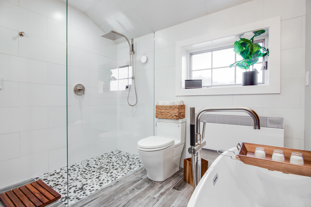 This is an example of a mid-sized contemporary master bathroom in New York with recessed-panel cabinets, grey cabinets, a freestanding tub, a curbless shower, a one-piece toilet, black and white tile, ceramic tile, grey walls, ceramic floors, an undermount sink, granite benchtops and an open shower.