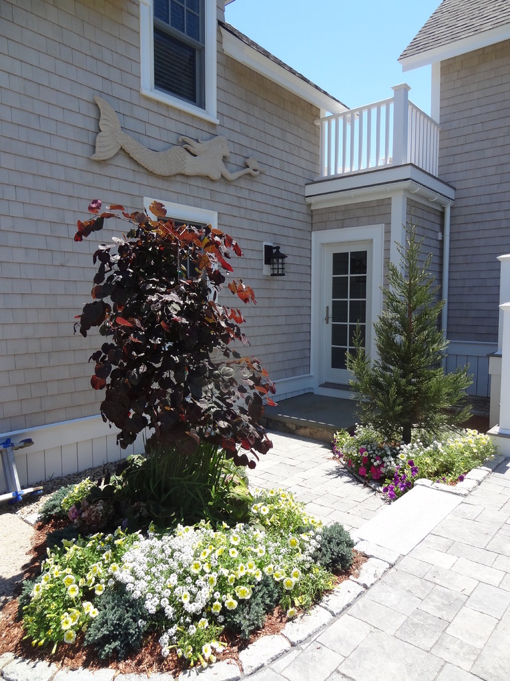 Photo of a large contemporary front yard full sun driveway for summer in Boston with natural stone pavers.