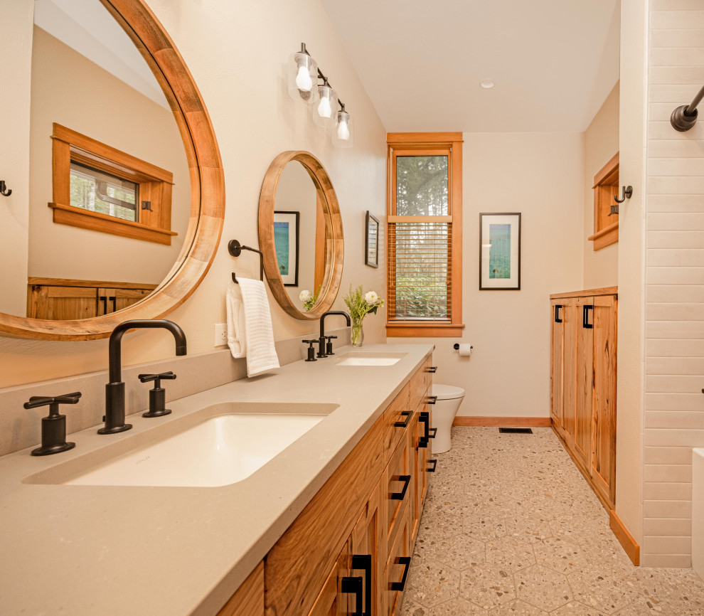 Mid-sized mountain style kids' gray tile and porcelain tile terrazzo floor, gray floor and double-sink alcove bathtub photo with shaker cabinets, medium tone wood cabinets, a one-piece toilet, beige walls, an undermount sink, quartz countertops, gray countertops, a niche and a freestanding vanity