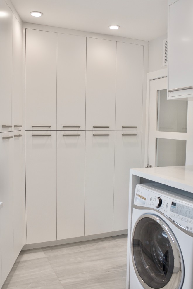 This is an example of a large modern galley utility room in Miami with an utility sink, flat-panel cabinets, white cabinets, quartz benchtops, white walls, marble floors and a side-by-side washer and dryer.