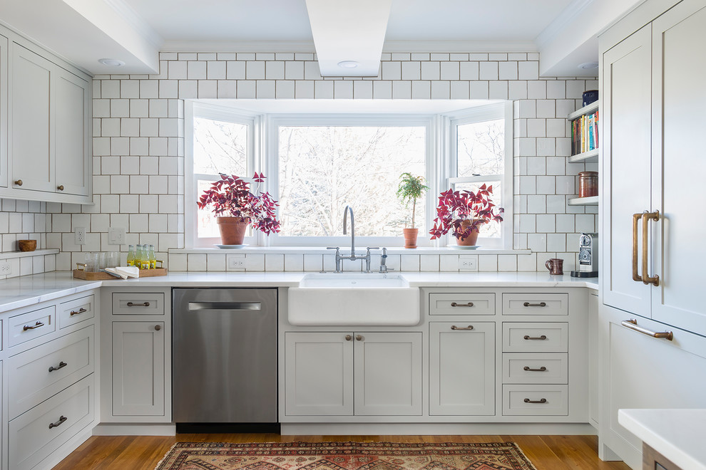 Inspiration for a large transitional u-shaped kitchen in Minneapolis with grey cabinets, marble benchtops, white splashback, stainless steel appliances, no island, a farmhouse sink, shaker cabinets and medium hardwood floors.